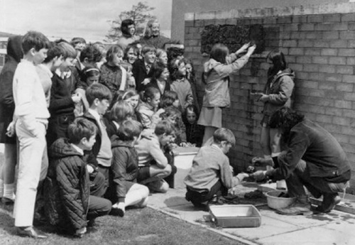 Children cementing their tiles to a wall. 1970